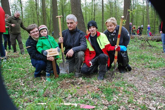 Theo Teichmann aus Kleinosterhausen, der im Mai drei Jahre alt wird, durfte fast alles selbst machen: seine Roteiche in die vorbereitete Grube stellen, Erde hineinschaufeln, sie festtreten (verdichten) und anschlie&szlig;end das tun, worauf er den ganzen Tag schon gewartet hatte: gie&szlig;en. Forstwirtlehrling Caroline Fischer (zweite von rechts) half vielen beim Pflanzen mit Rat und Tat. (Foto: Jochen Miche)
