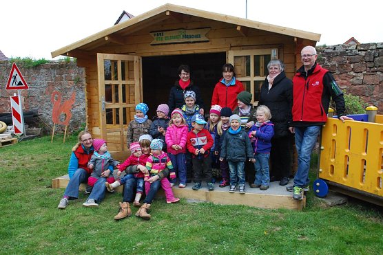 Gl&uuml;ckliche Kinder und Erwachsene vor dem "Haus der Entdecker". Im Hintergrund stehend (v.l.): Scheck&uuml;berbringerin Elfie Schubert, Kita-Leiterin Anke Rabenhold, Oberb&uuml;rgermeisterin Jutta Fischer und Ortsb&uuml;rgermeister J&uuml;rgen Grobe. (Foto: Jochen Miche)