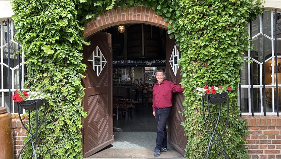 Der Hausherr im blühenden Innenhof vor der rustikalen Niederlage (Foto: oas) Der Hausherr im blühenden Innenhof vor der rustikalen Niederlage (Foto: oas)
