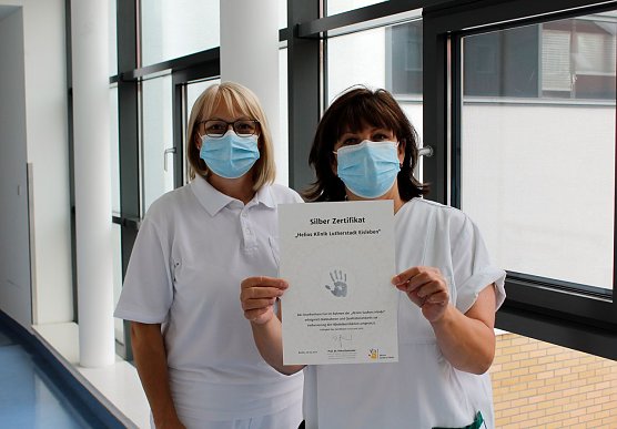 Steffi John und Katharina Blessin, Fachschwestern f&uuml;r Krankenhaushygiene, pr&auml;sentieren das Silber-Zertifikat der Aktion Saubere H&auml;nde (Foto: Helios Kliniken Mansfeld-S&uuml;dharz)