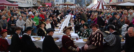 Bild: Die Honoratioren Eislebens, Vertreter der Kreisverwaltung, Menschen mit dem Nachnamen Luther und Geburtstagsg&auml;ste aus dem Publikum heute Nachmittag an der auf dem Marktplatz der Lutherstadt aufgebauten Tafel. Vor ihnen eine elf Meter lange Stolle, die anschlie&szlig;end gemeinsam mit dem Publikum vernascht wurde.
