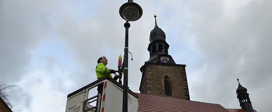 Bild: Daniel N&ouml;thlich von den Stadtwerken Hettstedt montiert vom Hubsteiger aus die weihnachtliche Lichterdekoration an Laternen der Innenstadt.