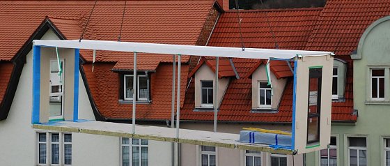 Bild: B&uuml;ro mit Aussicht. Dieses Bauteil schwebte vom Lkw hoch hinaus &uuml;ber das Ger&uuml;st, hinunter in die Reihe der bereits platzierten Module.