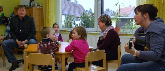 Bild: Ganz spontan nahm Erzieherin Katrin Steinbr&uuml;ck die Gitarre und sang gemeinsam mit den Kindern den G&auml;sten Lieder vor. Vorher hatte Norbert Born mit zwei Liedern &uuml;berrascht. Die Erzieherin am Fenster ist Elisabeth Liener.