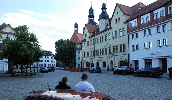 Bild: Zwei verhinderte Spazierg&auml;nger betrachten, ans Auto gelehnt, den menschenleeren Markt. Der zehnte Hettstedter Spaziergang fiel, wie schon der achte und neunte, aus. Stilles Ende einer kleinen Revolte.