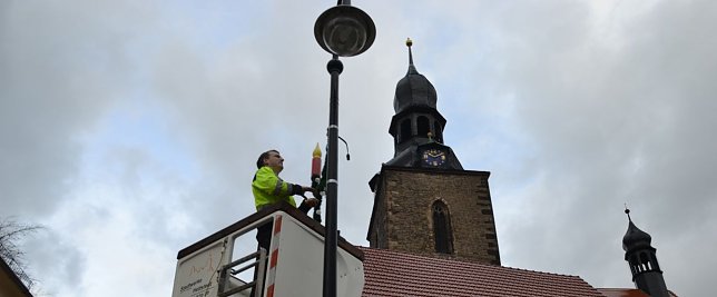 Bild: Daniel N&ouml;thlich von den Stadtwerken Hettstedt montiert vom Hubsteiger aus die weihnachtliche Lichterdekoration an Laternen der Innenstadt.