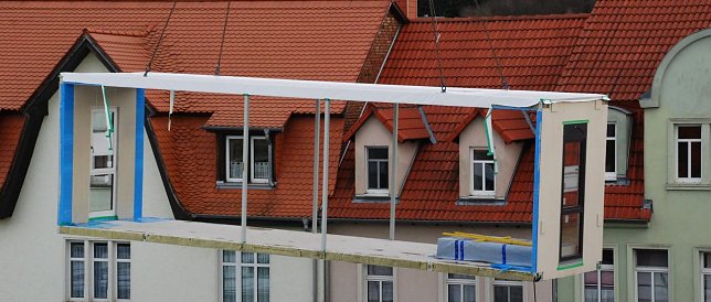 Bild: B&uuml;ro mit Aussicht. Dieses Bauteil schwebte vom Lkw hoch hinaus &uuml;ber das Ger&uuml;st, hinunter in die Reihe der bereits platzierten Module.