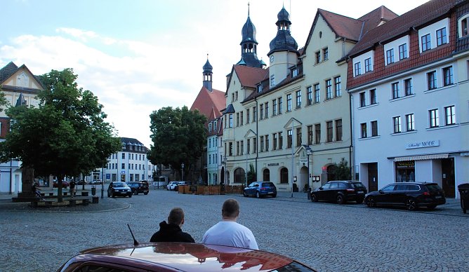 Zwei verhinderte Spazierg&auml;nger betrachten, ans Auto gelehnt, den menschenleeren Markt. Der zehnte Hettstedter Spaziergang fiel, wie schon der achte und neunte, aus. Stilles Ende einer kleinen Revolte. (Foto: J. Miche)