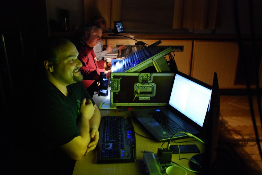 Nur im Licht ihrer Monitore und Pulte bei der Arbeit (von vorn): Norman Meyer (Videoproduktion), Hans-Heinrich St&uuml;ber (Tontechnik) und Felix Lehm (Beleuchtung).