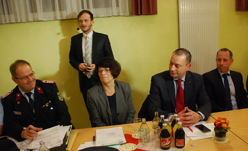 Moderator Florian Mydlak (stehend) und Kreisjugendfeuerwehrwart Thomas Reinhardt dankten w&auml;hrend der Verbandsversammlung einigen starken Partnern der Feuerwehr: neben der Landr&auml;tin dem Vertreter der Kreissparkasse, Vorstand Michael N&auml;her, und J&ouml;rg Fischer von Wichmanns Systemhausgruppe (von links). 